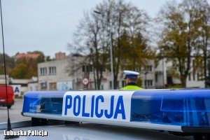 napis policja, w tle policjant obserwuje ruch na drodze