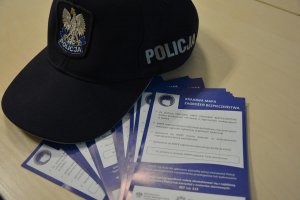 czapka policyjna i ulotki dotyczące krajowej mapy zagrożeń bezpieczeństwa