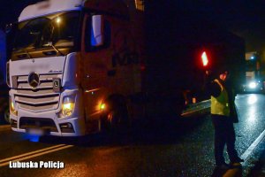policjantka kieruje ruchem, obok odzyskane ciężarówki