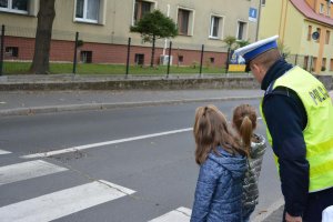 policjant z dziećmi przy przejściu dla pieszych