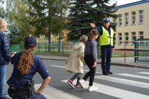 dzieci pod okiem policjantów przechodzą przez przejście dla pieszych