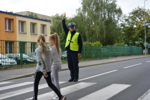 dzieci pod okiem policjanta przechodzą przez przejście dla pieszych