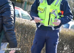policjant rozmawia z pieszym i trzyma ulotki
