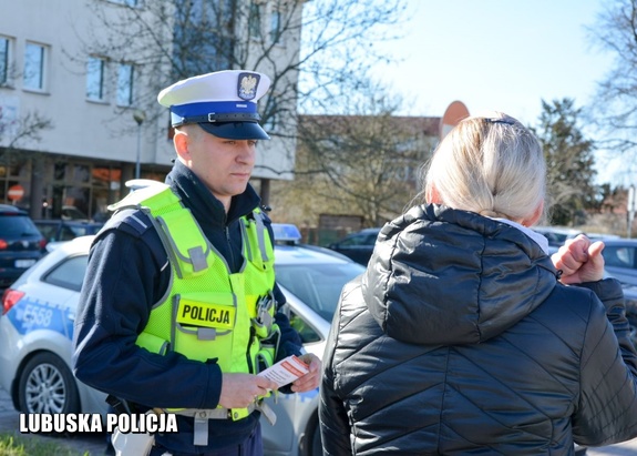 policjant rozmawia z pieszym i trzyma ulotki