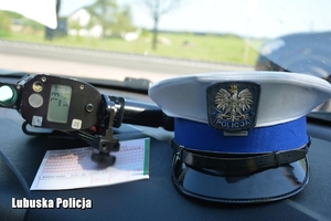Druk mandatu karnego, urządzenie do pomiaru prędkości i czapka leżące na podszybiu