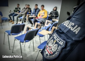 emblemat na bluzie policyjnej, w tle mężczyźni
