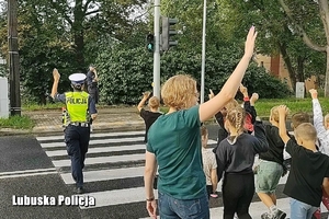 Dzieci, nauczycielka i policjanci przechodzą przez jezdnię