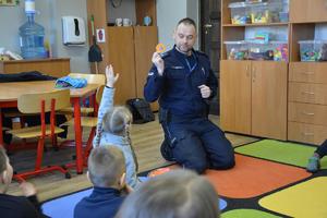 policjant rozmawia z dziećmi i pokazuje odblaski