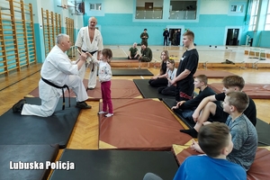 Karatecy, dzieci i terytorialsi ćwiczą na materacach.