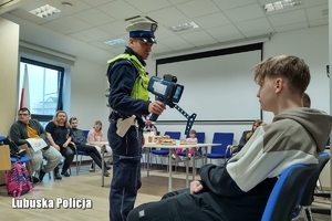 Policjant pokazuje dzieciom obraz na laserowym mierniku prędkości.