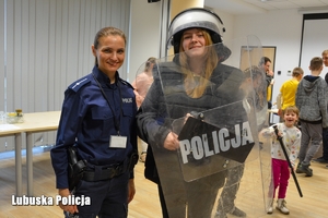policjanta i dziewczyna ubrana w komplet przeciwuderzeniowy wykorzystywany do zabezpieczenia imprez masowych