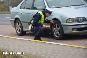 Policjant sprawdza stan ogumienia w pojeździe