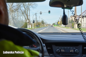 policjanci jadą radiowozem, w tle zielone światło na sygnalizatorze