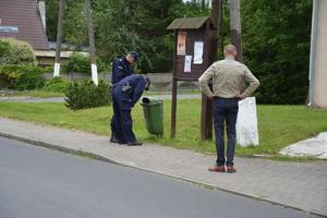 mężczyzna rozmawia z policjantami i zaglądają do śmietnika