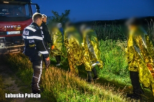 Policjanci i strażacy prowadzą mężczyzn.