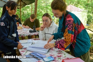 Policjantka w obecności osób odpowiedzialnych za organizację obozu kontroluje dokumentację