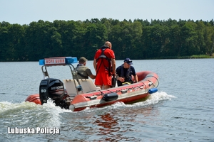 policjant, ratownik i strażnik leśny pływają łodzią motorową