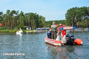 policjant, ratownik i strażnik leśny pływają łodzią motorową i obserwują zachowanie osób w wodzie