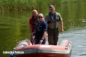 policjant, ratownik i strażnik leśny pływają łodzią motorową