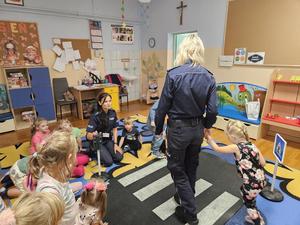 dzieci wraz z policjantkami uczą się przechodzenia przez jezdnię