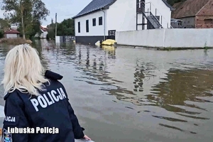 policjantka na łodzi, w tle zalane posesje