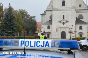 napis policja na radiowozie, w tle policjant