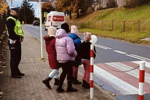 policjant z dziećmi przy przejściu dla pieszych