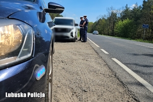 niebieskie światło w radiowozie, w tle policjanci podczas kontroli drogowej