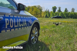 napis policja na radiowozie, w tle dron