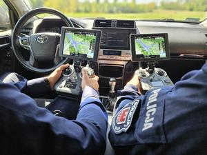 policjanci w radiowozie trzymają urządzenia do obsługi drona