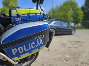 napis policja na motocyklu, w tle samochód