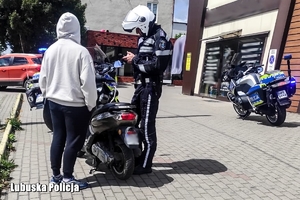 policjant podczas kontroli motorowerzysty, obok policyjny motocykl