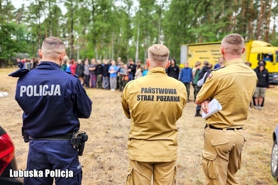 policjant i strażacy kontrolują obóz harcerski