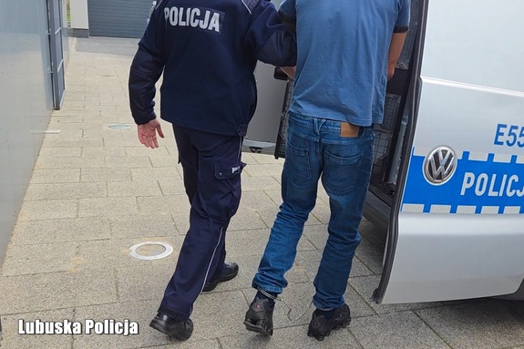 policjant prowadzi zatrzymanego do radiowozu
